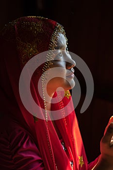 An Giang, Vietnam - Sep 6, 2016: Portrait of Vietnamese muslim girl wearing traditional red dress in a champa village, Khanh Hoan