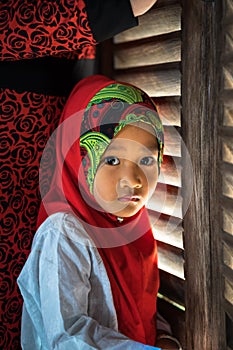 An Giang, Vietnam - Sep 6, 2016: Portrait of Vietnamese muslim little girl wearing traditional red dress in a champa village, Khan