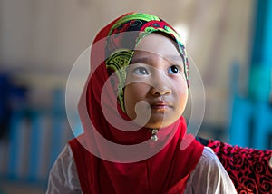 An Giang, Vietnam - Sep 6, 2016: Portrait of Vietnamese muslim little girl wearing traditional red dress in a champa village, Khan