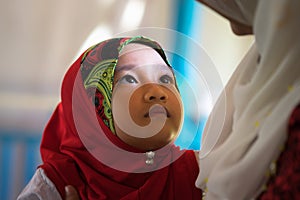 An Giang, Vietnam - Sep 6, 2016: Portrait of Vietnamese muslim little girl wearing traditional red dress in a champa village, Khan