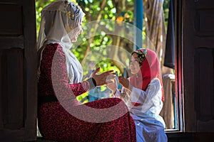 An Giang, Vietnam - Sep 6, 2016: Vietnamese muslim girl wearing traditional red dress playing with her sister in a champa village,