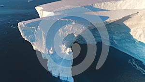 Giant Antarctic blue iceberg cave in sunset light