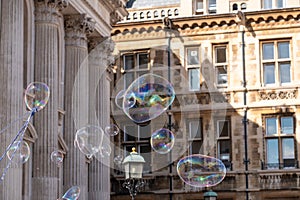 Giant bubbles blown for tourists outside Senate House and Gonville and Caius College in Cambridge town centre, UK