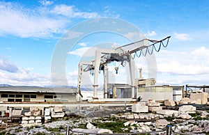 Giant crane on tracks being used to reconstruct Parthenon on Athens Acroplis with pieces of the ruins organized in foreground