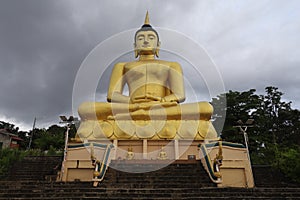 Giant golden Buddha against a stormy sky