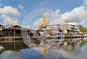 The Giant Golden Buddha in Wat Paknam Phasi Charoen Temple in Phasi Charoen district with boat on Chao Phraya River at noon,