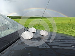 Giant hailstones displayed on a black car after a powerful storm has passed