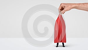 A giant hand taking off a red drapery from a hidden businessman on white background.