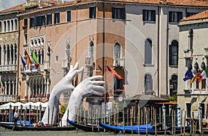 Giant hands rise from the water of Grand Canal to support the Ca' Sagredo Hotel to call attention about climate change