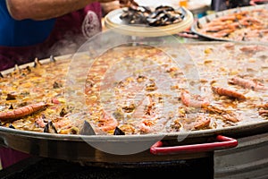 Adding shrimp and shellfish to a giant paella during cooking.