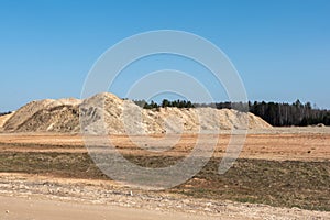 Giant pile of sand against the blue sky. Sand extraction mine.