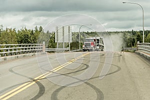 Giant red dump truck makes way down to the trans canada on road with tire markings