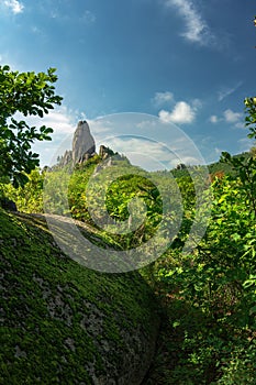 A giant rock against a blue sky with clouds.