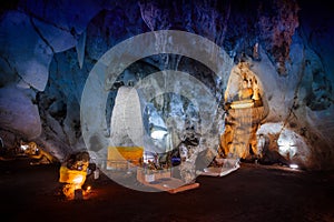 Giant underground cave in Asia with huge stalagmites, stalactites and buddha statue in the center of the hall