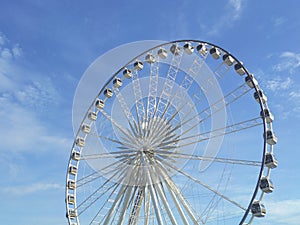 Giant wheel provides rides for viewing the city White clouds in the blue sky in background