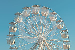 Giant white observation ferris wheel for panoramic view in amusement park is popular entertaining ride, shot against blue sky on