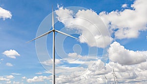The giant wind turbine stands against cloudy blue sky background
