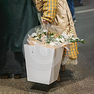 Gift basket of flowers in hands of fashionable elderly woman