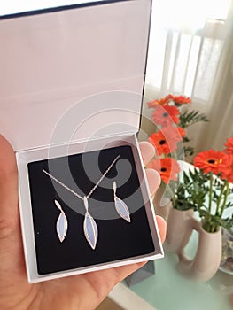 Gift for beloved one. The set of earrings and necklace in a gift box. Jewellery and flowers.