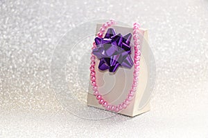 Gift with bow, jewelry and cosmetics for women on brilliant background