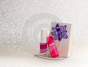 Gift with bow, jewelry and cosmetics for women on brilliant background