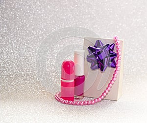 Gift with bow, jewelry and cosmetics for women on brilliant background