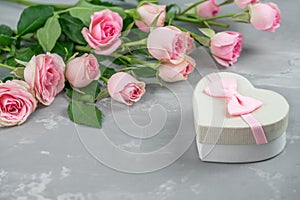 Gift box and a beautiful bouquet of pink roses on a gray background