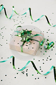 Gift box with a beautiful green bow on a light background with confetti stars