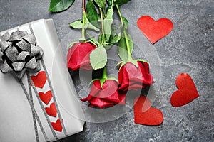 Gift box and beautiful roses on grey background