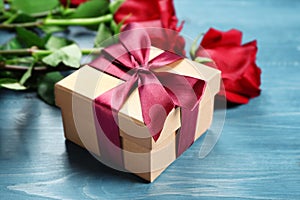 Gift box and beautiful roses on wooden background