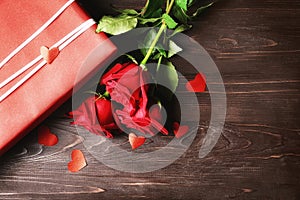 Gift box and beautiful roses on wooden background