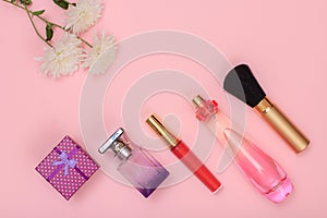 Gift box, bottles of perfume, brush and flowers on a pink background. Women cosmetics and accessories.