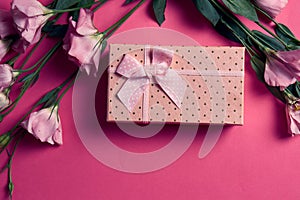 Gift box and bouquet of flowers on pink background bow holidays top view