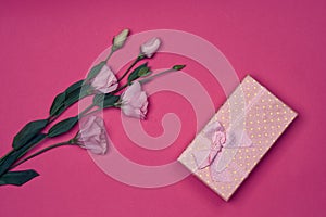 Gift box and bouquet of flowers on pink background bow holidays top view