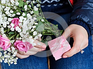 Gift box and a bouquet of roses woman in hands