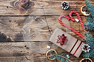 Gift box with bow. Christmas tree and decorations, cane caramel and oranges nuts Wooden background copy space