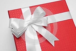 Gift box with bow on light grey background, closeup