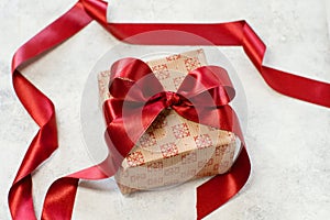 Gift box with bow made with red satin ribbon on a table