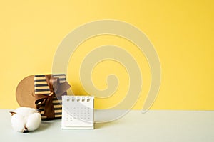 Gift box and calendar on gray table. yellow wall background