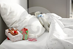 Gift box with candy cane and gingerbread on bed in children`s room. St. Nicholas Day tradition
