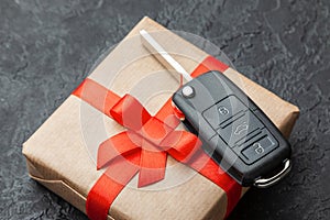 Gift box with car keys with remote control alarm system with red ribbon bow.