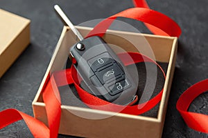 Gift box with car keys with remote control alarm system with red ribbon bow.