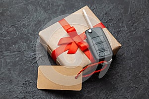 Gift box with car keys with remote control alarm system with red ribbon bow and label.