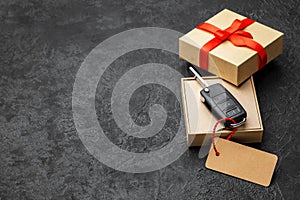 Gift box with car keys with remote control alarm system with red ribbon bow and label. Copy space