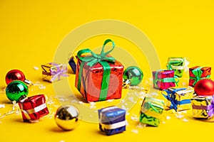 Gift box with a Christmas present on a yellow background, among the New Year`s decorations