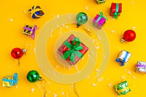 Gift box with a Christmas present on a yellow background, among the New Year`s decorations