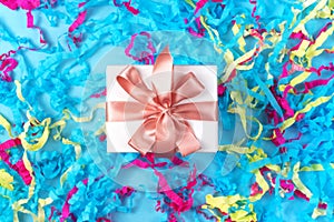 Gift box with colored streamers bright blue background top view of Flat lay