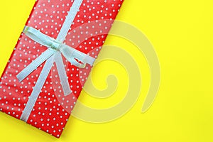Red rectangular box in a festive wrapping on a yellow background.