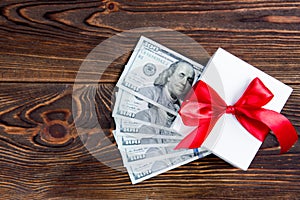 Gift box with dollars on wooden background