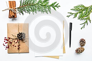 Gift box in eco paper and a letter on white background. Christmas or other holiday concept, top view, flat lay